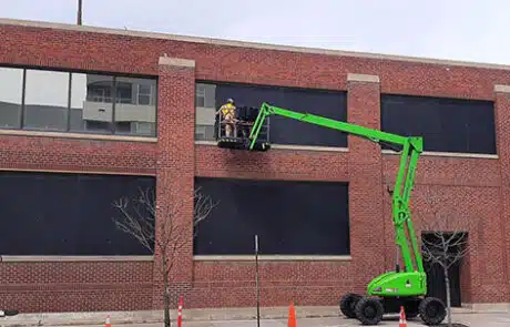 RSI crew on a boom lift boarding up the upper windows of a building