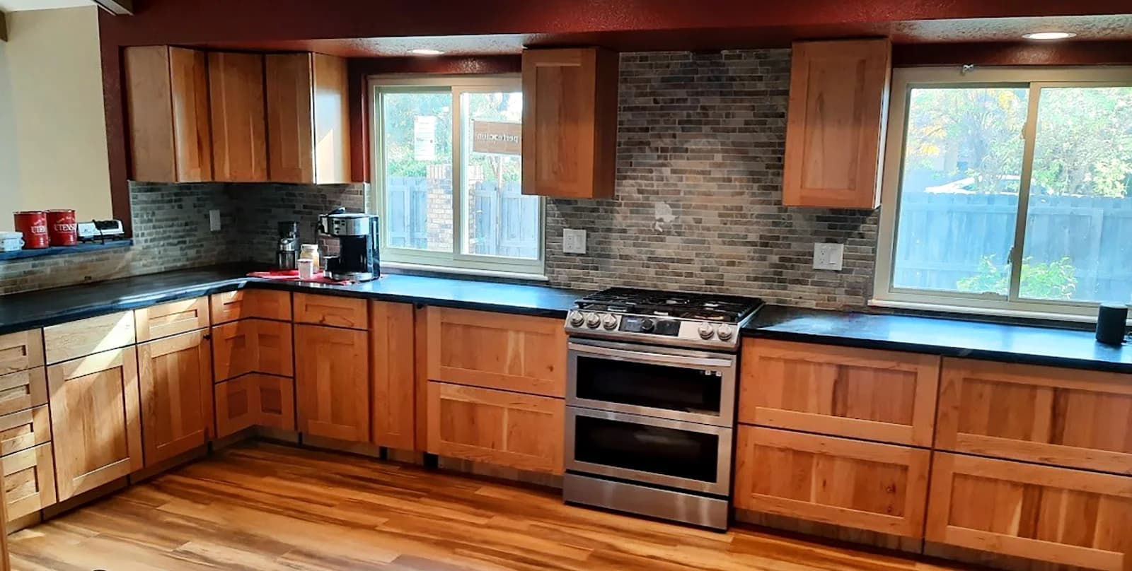 A kitchen RSI rebuilt after water damage, with wood cabinets, a stone backsplash and a stainless range